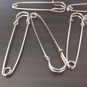 Macro shot of polished silver safety pins for shawls on dark wooden background