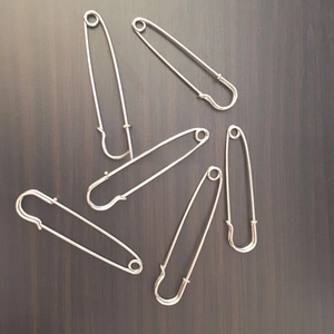 Detailed view of six polished silver metal safety pins for scarves and shawls on wood