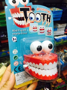 Funny wind-up jumping teeth toy in red gums for prank gifts and Halloween surprises