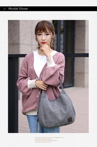 Outdoor shot of a large grey canvas tote bag with brown leather straps and vintage logo