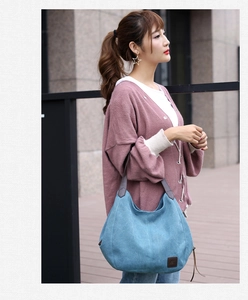 Detailed view of blue canvas tote bag with brown leather handles and brand logo tag