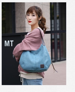 Sky blue canvas tote bag with brown leather straps shown on a model in an urban setting