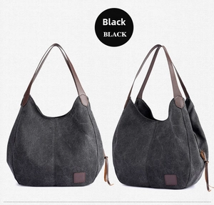 Front and side view of a black canvas tote bag with brown leather handles and brand label