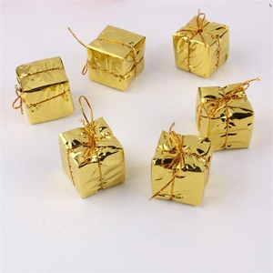 Detailed view of six miniature gold gift box ornaments with shiny foil texture and bows