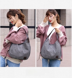 Detail of dark grey canvas tote bag with brown leather handles and brand logo tag
