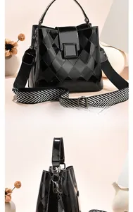 Detail of black quilted bucket bag with woven wide shoulder strap and textured leather finish