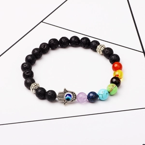 Lava stone chakra bracelet with Hamsa Hand and Evil Eye charms on a white surface