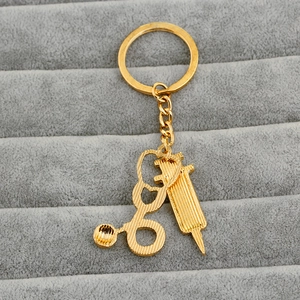 Macro view of gold stethoscope and syringe charms on a medical themed keychain