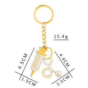 Golden stethoscope and syringe medical keychain with white enamel finish on white background