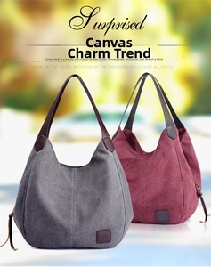 Detailed view of large canvas shoulder bags in grey and wine red with leather accents