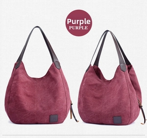 Detail view of purple canvas tote bag with brown leather handles and side zipper pocket