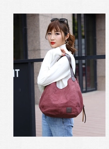 Outdoor shot of a burgundy canvas tote bag with brown leather handles and multi-pockets