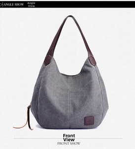 Front view of grey canvas hobo bag with brown leather straps and logo patch