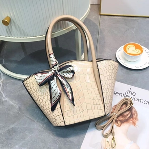 Close-up of beige crocodile texture tote bag with silk scarf and detachable strap