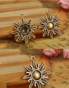 Macro view of two 25mm antique bronze sun charms for DIY jewelry making accessories