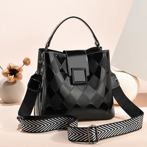 Chic black patent leather bucket bag with quilted patterns and a wide woven shoulder strap