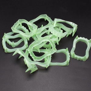 Close-up of multiple glow-in-the-dark green vampire fangs made of plastic for Halloween