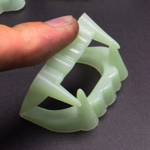 Detailed close-up of glow-in-the-dark vampire fangs props for Halloween pranks