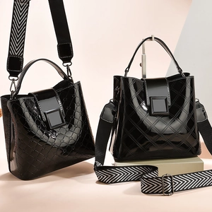 Glossy black quilted bucket bag set with embossed floral details and woven shoulder strap