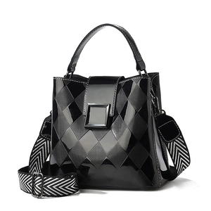Glossy black patent leather bucket bag with quilted patterns and wide herringbone strap