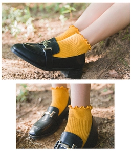Close-up of yellow ribbed cotton ankle socks with ruffled edge detail and black loafers