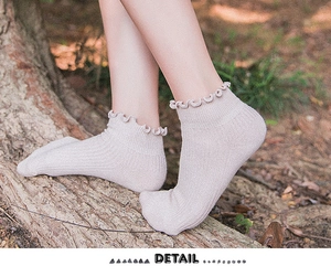 Detailed view of beige cotton socks with vertical ribbing and wavy ruffled edges