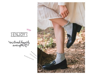 Detail of grey ribbed cotton socks with ruffled edges worn with black buckle loafers