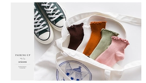 Detail of five pairs of cotton lettuce edge socks in earth tones inside a canvas bag