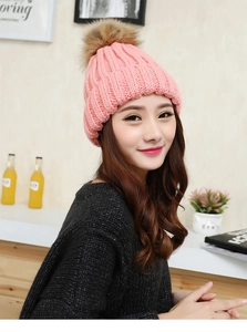 Detail of pink cable knit beanie featuring a soft brown faux fur pom-pom on top
