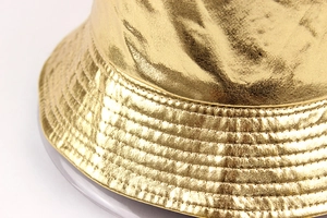 Close-up of metallic gold bucket hat featuring reinforced stitching on the brim
