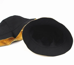 Detailed view of reversible bucket hat showing black fabric and metallic gold lining