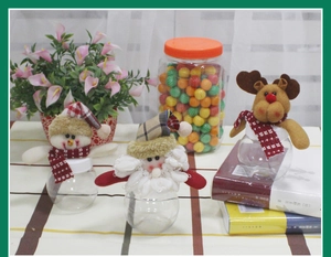 Close-up of small round Christmas candy jars with plush Santa, Snowman and Reindeer tops