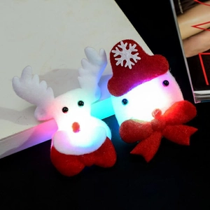 Close-up of glowing LED Christmas hair clips with white reindeer and red snowman designs