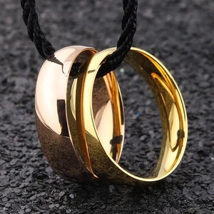 Polished gold and rose gold stainless steel rings for men on a dark textured surface