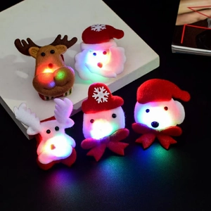 Macro shot of five plush LED Christmas brooches featuring Santa, reindeer, and snowmen