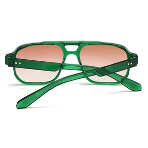 Close-up of green translucent pilot sunglasses with gold star rivets and gradient lenses