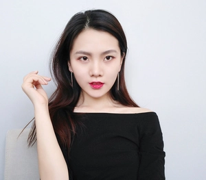 Detail of rose gold minimalist long bar drop earrings on model with black top