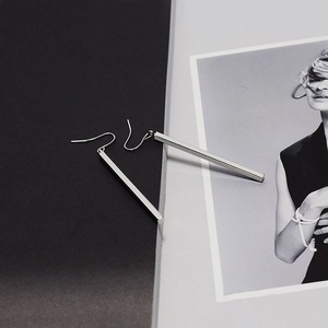 Polished silver geometric long bar earrings with minimalist ear hooks on magazine