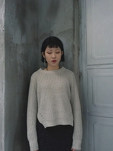 Close-up of light grey chunky knit sweater with round neck and side slit details