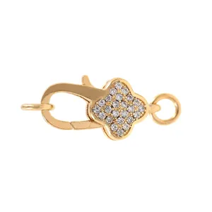 Dettaglio di una chiusura a moschettone a quadrifoglio dorata con pavé di zirconi