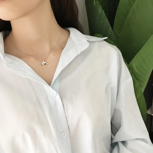 Close-up of a 925 sterling silver dolphin tail necklace worn by a model in a white shirt