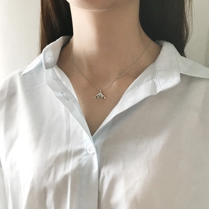 Minimalist silver dolphin tail necklace worn by a model on a white shirt background