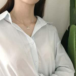 Detailed close-up of a 925 sterling silver whale tail pendant necklace on a model