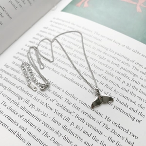 Macro view of S925 sterling silver dolphin tail pendant necklace on book pages