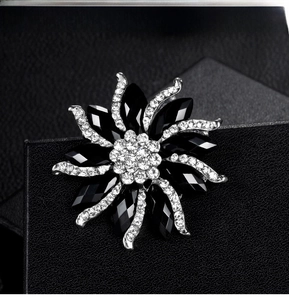 Detail of silver alloy flower brooch featuring black resin petals and sparkling rhinestones