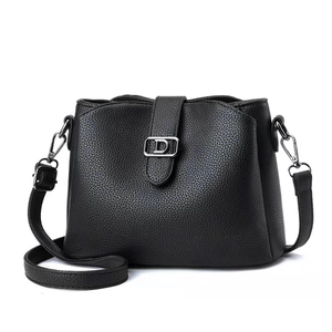 Detail of black lychee grain leather crossbody bag with silver D-buckle and strap