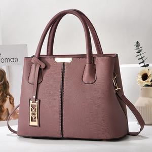 Detailed macro view of dust pink lychee leather texture and golden metal hardware on bag