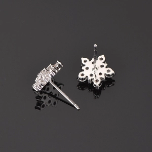 Detailed macro view of snowflake earrings with AAA zircons on a reflective black background