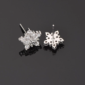 Macro shot of silver snowflake earrings with AAA cubic zirconia on black mirror