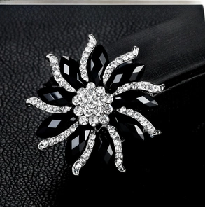 Detailed close-up of a flower brooch with black crystals and diamonds on leather